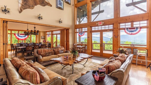 A spacious living area with leather sofas, a wooden coffee table, and large windows offering a view of the outdoors.