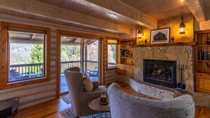 Ein gemütliches Blockhaus mit Kamin aus Stein, Holzwänden und einem Balkon mit Sitzgelegenheit.