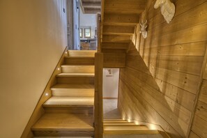 Una escalera de madera con barandilla que conduce a una habitación con paredes y techo de madera.