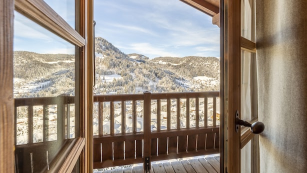 Un balcon en bois offrant une vue sur des montagnes enneigées.