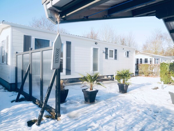A mobile home with a screened porch and a sign that reads "RENESSE". - Holiday Chalet/Mobilelhome "Wüstenblume" (Renesse)