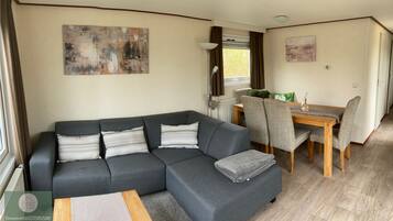 A modern living room with a grey sectional sofa, a wooden coffee table, and a dining area with a wooden table and grey chairs.