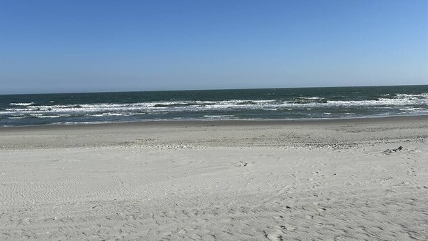 Una playa con cielo despejado y mar tranquilo.