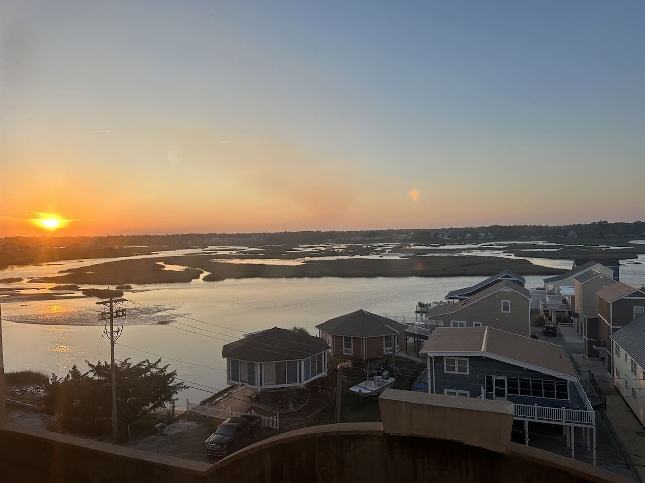 Un quartier résidentiel avec des maisons situées près d’une étendue d’eau, au coucher du soleil.