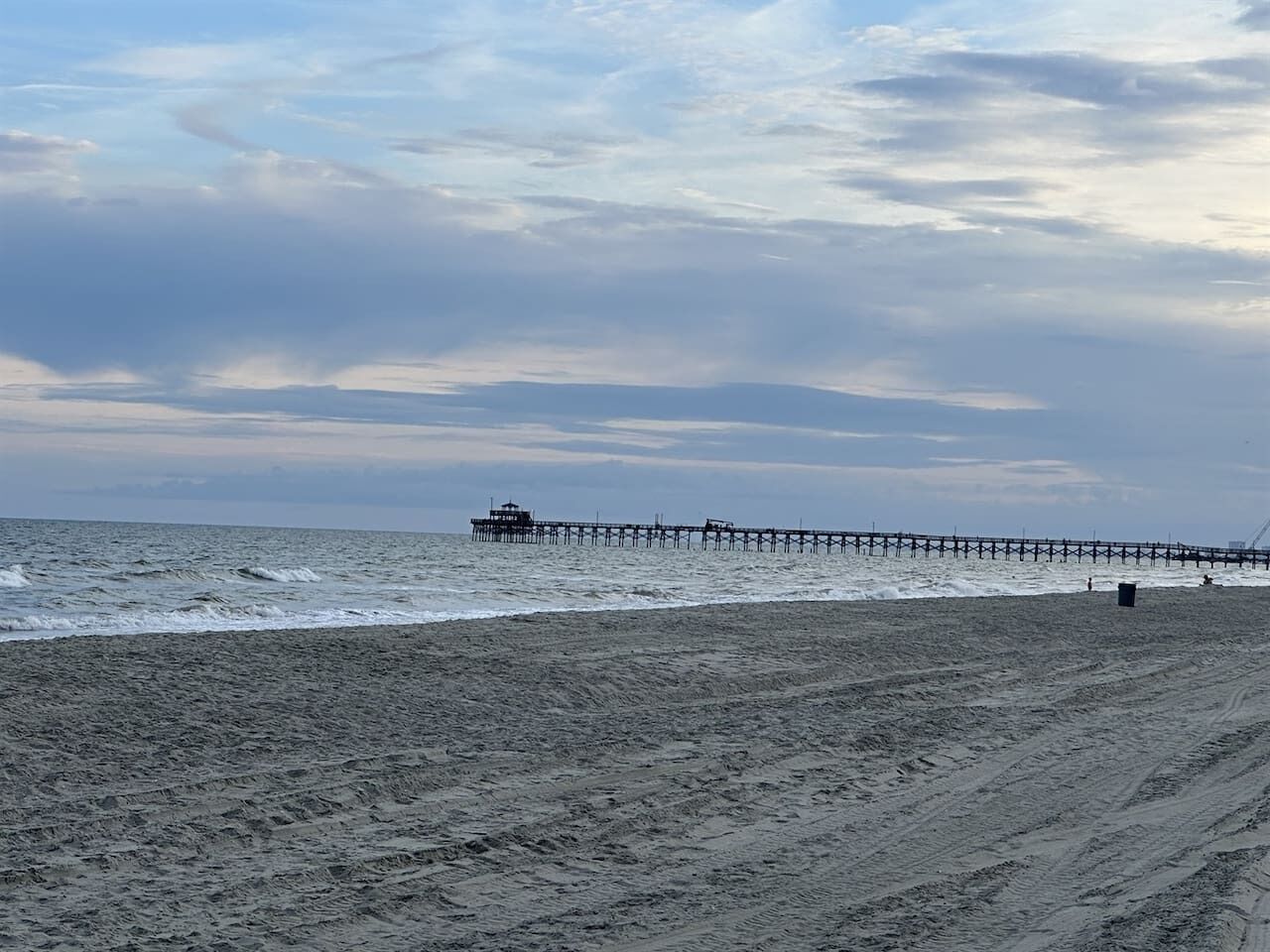 A beach with a pier extending into the ocean.