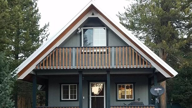 A two-story cabin with a balcony, a front door, and a satellite dish.