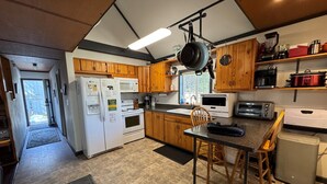 A kitchen with wooden cabinets, a microwave, a stove, a sink, and a dining area with a table and chairs.