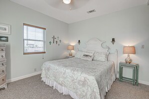 Une chambre à coucher comprenant un lit, deux tables de chevet avec des lampes, une commode, une fenêtre avec des stores et des éléments de décoration murale.