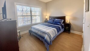 A bedroom with a bed, a window, a nightstand, and a dresser.