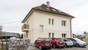 A two-story house with a tiled roof and a balcony. There are three cars parked in front. - Apartments Kamr'ca - room 2 & 5 with private bathroom (Ljubljana)