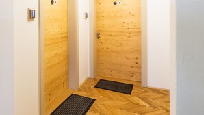 A hallway with wooden floors and two doors, each with a security keypad and a number sign. - Apartments Kamr'ca - room 2 & 5 with private bathroom (Ljubljana)