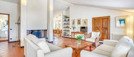 Un salón espacioso con sofás de cuero blanco, una mesa de centro de madera y una chimenea.