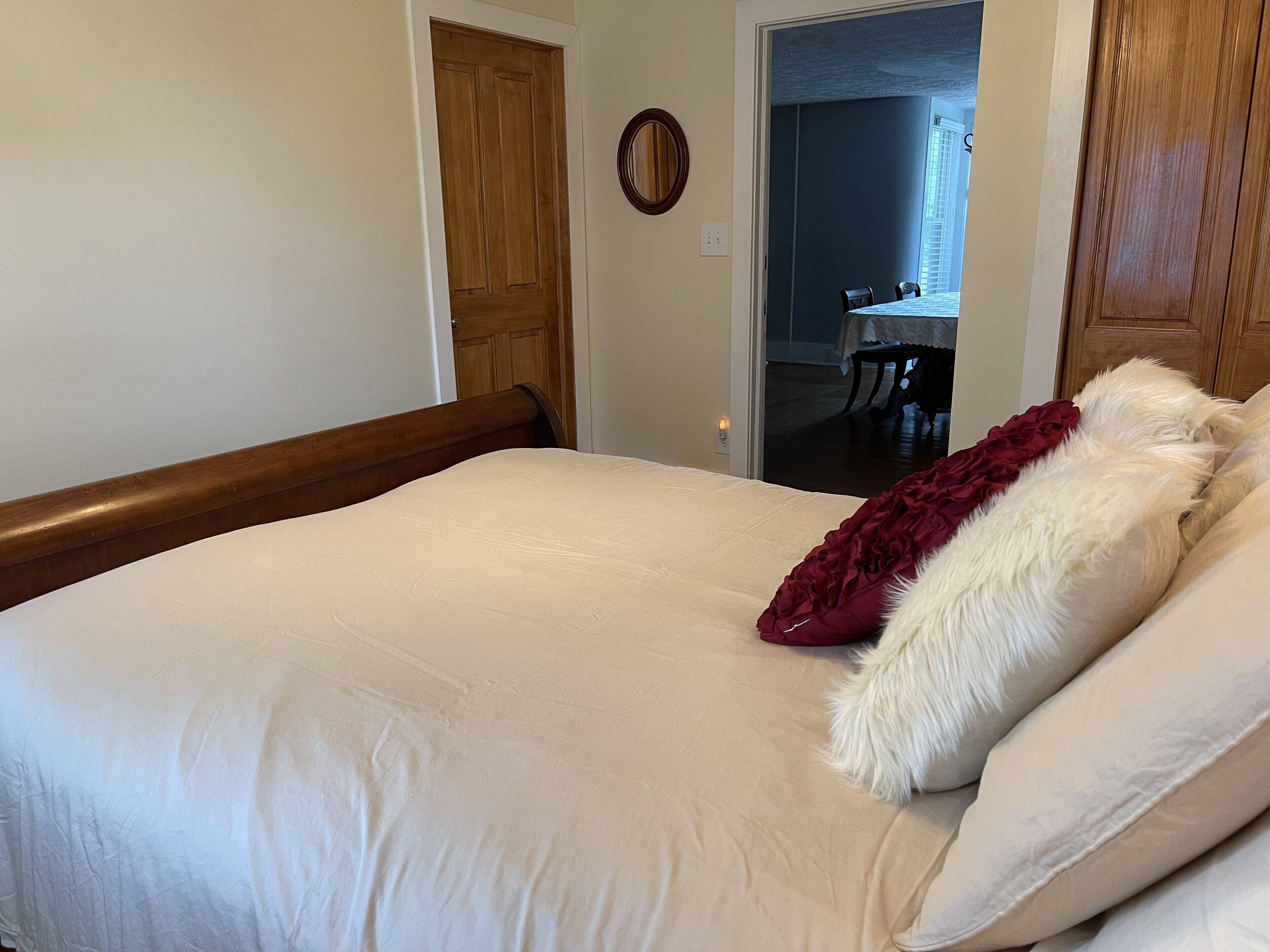 Une chambre à coucher avec un lit, une tête de lit en bois et une porte donnant sur un coin repas.