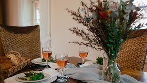 A dining table with two wine glasses, a basket of bread, and a vase with flowers.