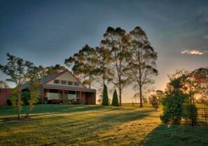 A house with a large lawn and tall trees in the background.