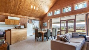 A spacious cabin with a wooden interior, a dining area, and a sofa.