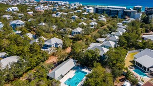 Zona residencial com várias casas, piscina e vista para o oceano.