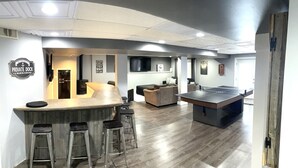 A modern kitchen with a bar area, a fireplace, and a ping pong table. - WolfDen Getaway-Winnebago Channel (Oshkosh)