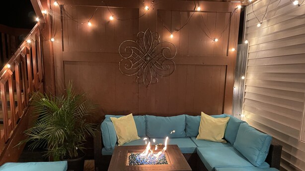 A cozy outdoor seating area with a sectional sofa, a fire pit, and string lights. - WolfDen Getaway-Winnebago Channel (Oshkosh)
