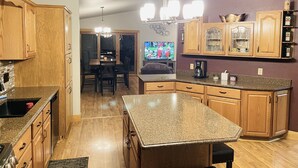 A modern kitchen with wooden cabinets, granite countertops, and a central island. - WolfDen Getaway-Winnebago Channel (Oshkosh)