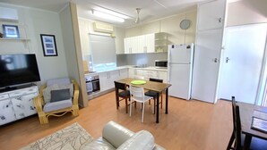 A compact living space with a kitchenette, a dining area, a sofa, and a television. - Exmouth Villas Unit 28 - This Villa is Perfect for groups and families alike (EXMOUTH)