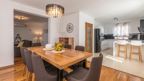 Eine moderne Küche mit weißen Schränken, einem schwarzen Kühlschrank und einem Holzes Esstisch mit vier Stühlen.