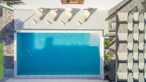 Ein rechteckiger Swimmingpool mit klarem, blauem Wasser, umgeben von einer gefliesten Terrasse.