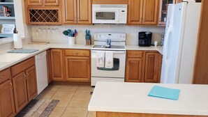 A kitchen with wooden cabinets, a white stove, a microwave, and a refrigerator.