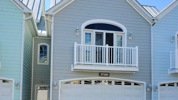A two-story house with a garage, a balcony, and a small porch.