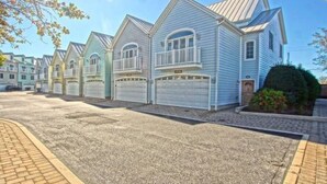 A row of single-story houses with attached garages, featuring a simple, functional design with gabled roofs and small front yards.