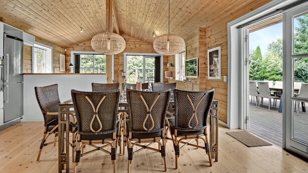 Un intérieur en bois avec un coin repas comprenant des chaises en osier et une table centrale.