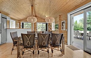 Een houten interieur met een eethoek, met rieten stoelen en een centrale tafel.