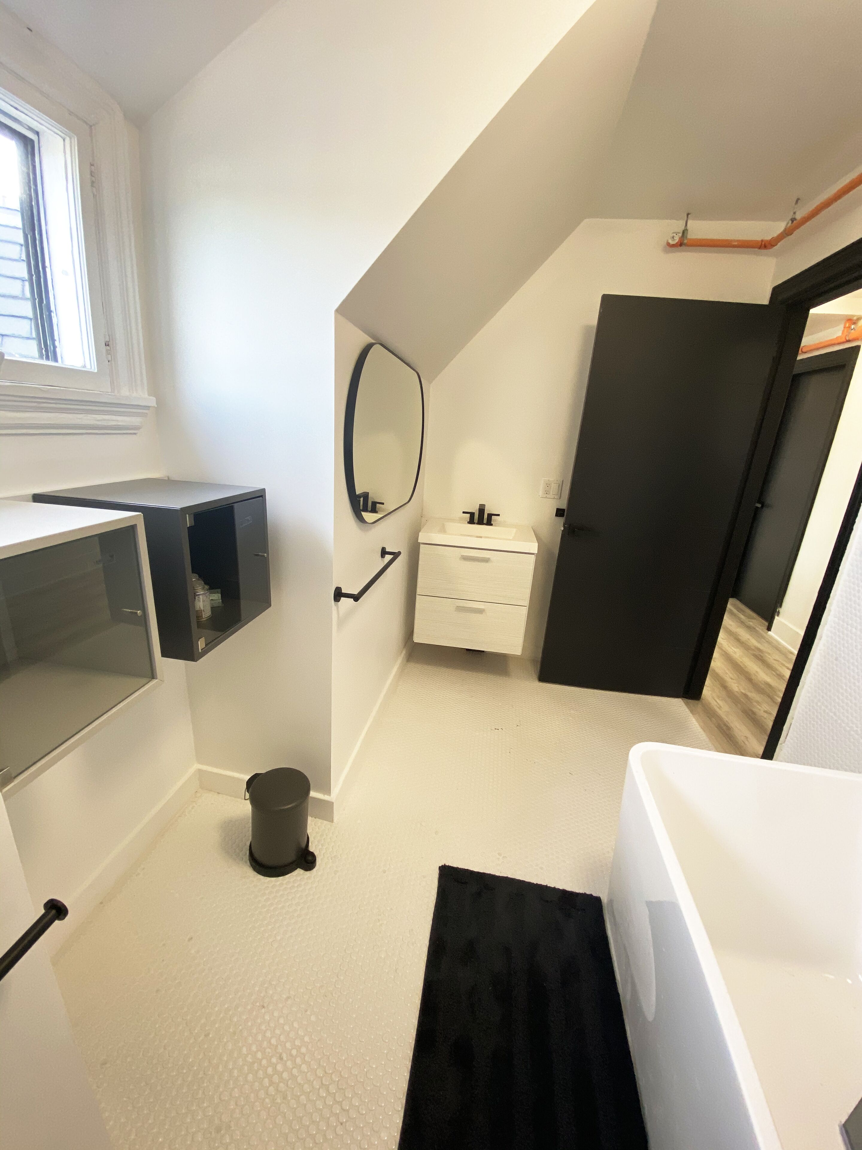 A compact, modern bathroom with a white sink, mirror, and toilet.