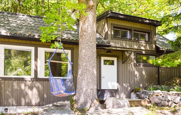 Een tweelaags huis met een veranda, een hangmat en een stenen muur.