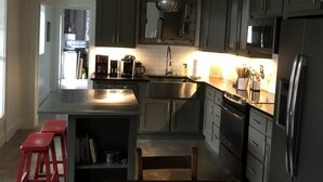A modern kitchen with dark cabinets, stainless steel appliances, and a central island with stools. - Lake Rabun Rental - Classic Waterside Home and Boathouse (Lakemont)