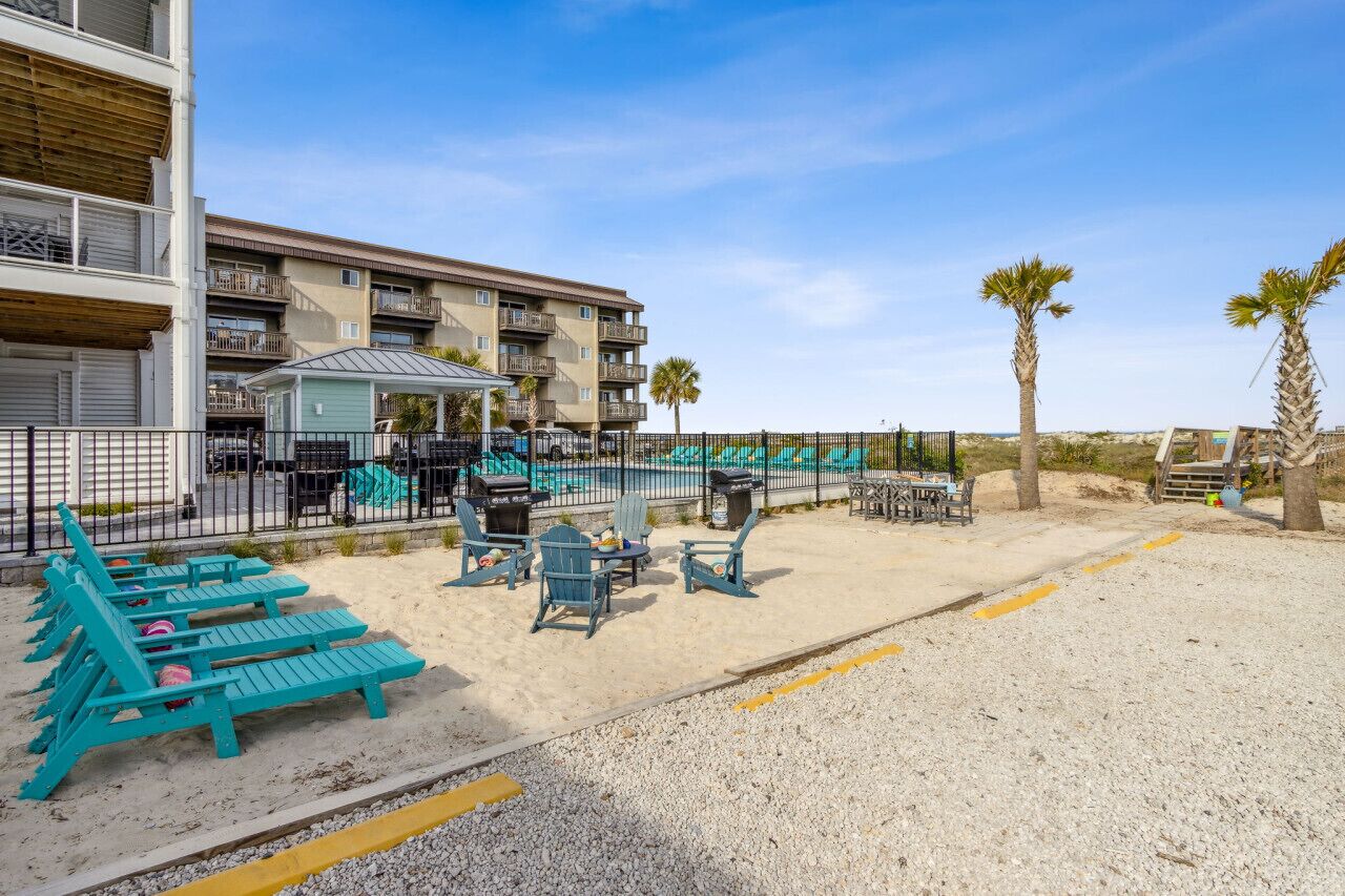 A beachfront hotel with a pool area, outdoor seating, and a view of the ocean.