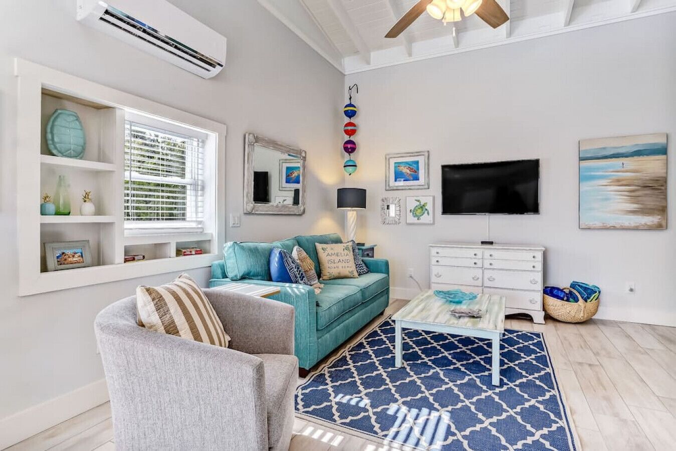 A living room with a teal sofa, a grey armchair, a coffee table, and a patterned rug.