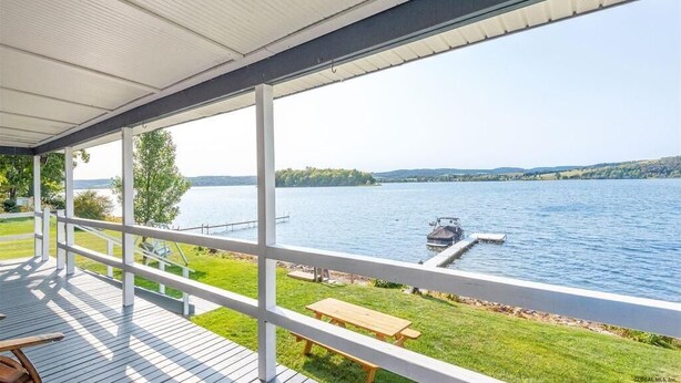 Une terrasse couverte avec vue sur un lac et un quai.