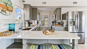 Una cocina moderna con una isla central, electrodomésticos de acero inoxidable y un reloj de estilo vintage.