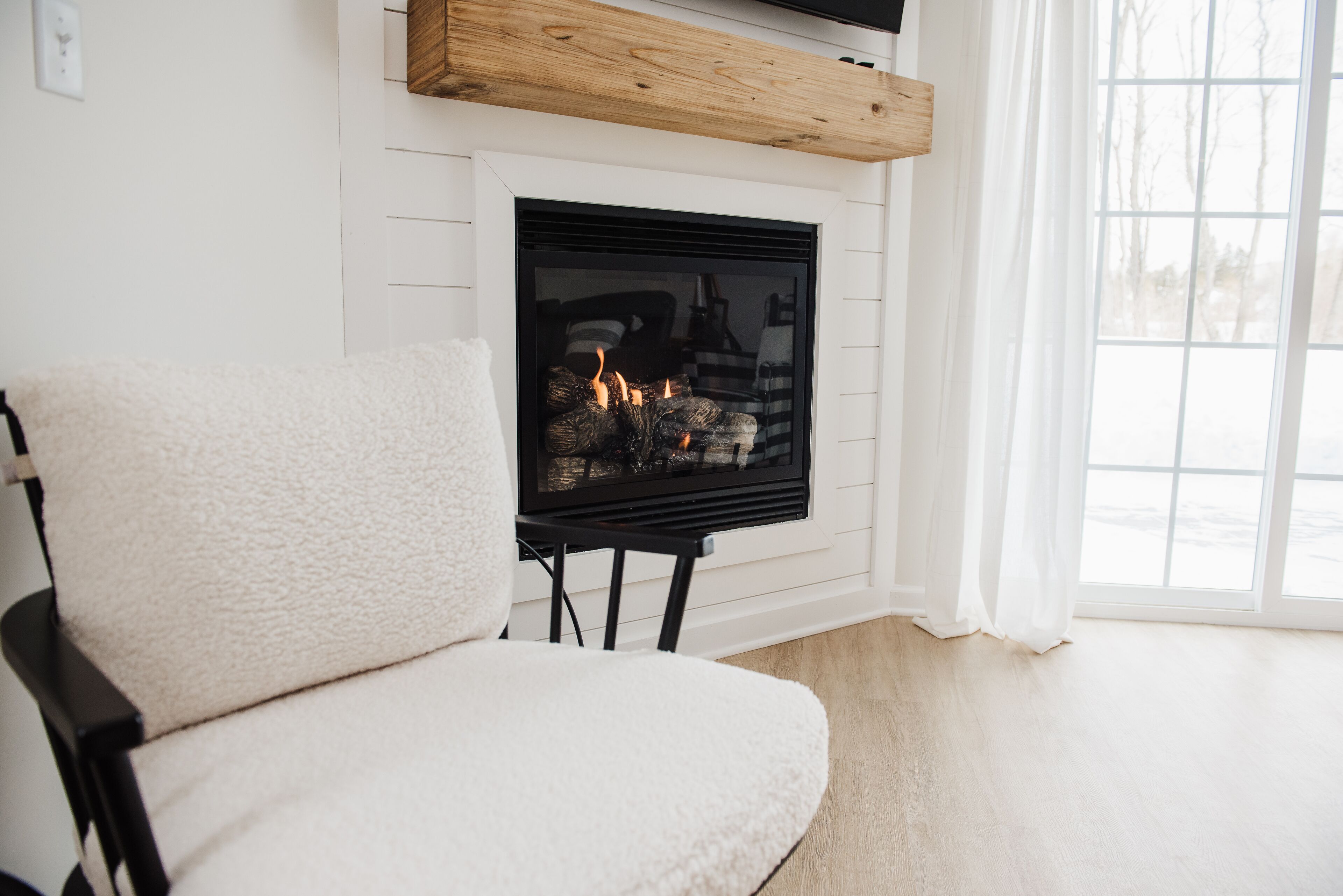 Una habitación acogedora con chimenea, un sillón mullido y un ventanal amplio.