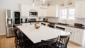A modern kitchen with white cabinets, stainless steel appliances, and a large island with chairs.