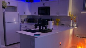 Una cucina moderna con mobili bianchi, un'isola centrale, un forno a microonde e un fornello.