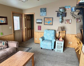 A cozy living room with a blue armchair, wooden furniture, and a fireplace.