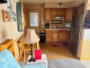 A compact kitchen with wooden cabinets, a stainless steel refrigerator, and a coffee maker.