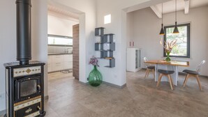A modern kitchen with a black stove, a dining area with a wooden table and chairs, and a decorative green vase.