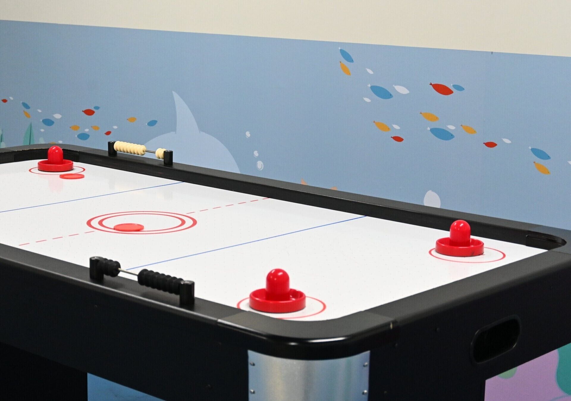 Ein Kicker mit vier roten Spielfiguren und einem schwarzen Spielstock.