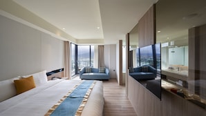 A modern hotel room with a large bed, a sofa, a TV, and a city view. - Lan Yang Seaview Hotel (Toucheng)