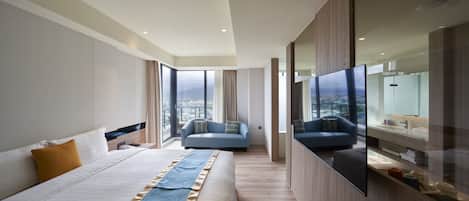 Een moderne hotelkamer met een groot bed, een bank, een televisie en uitzicht over de stad.
