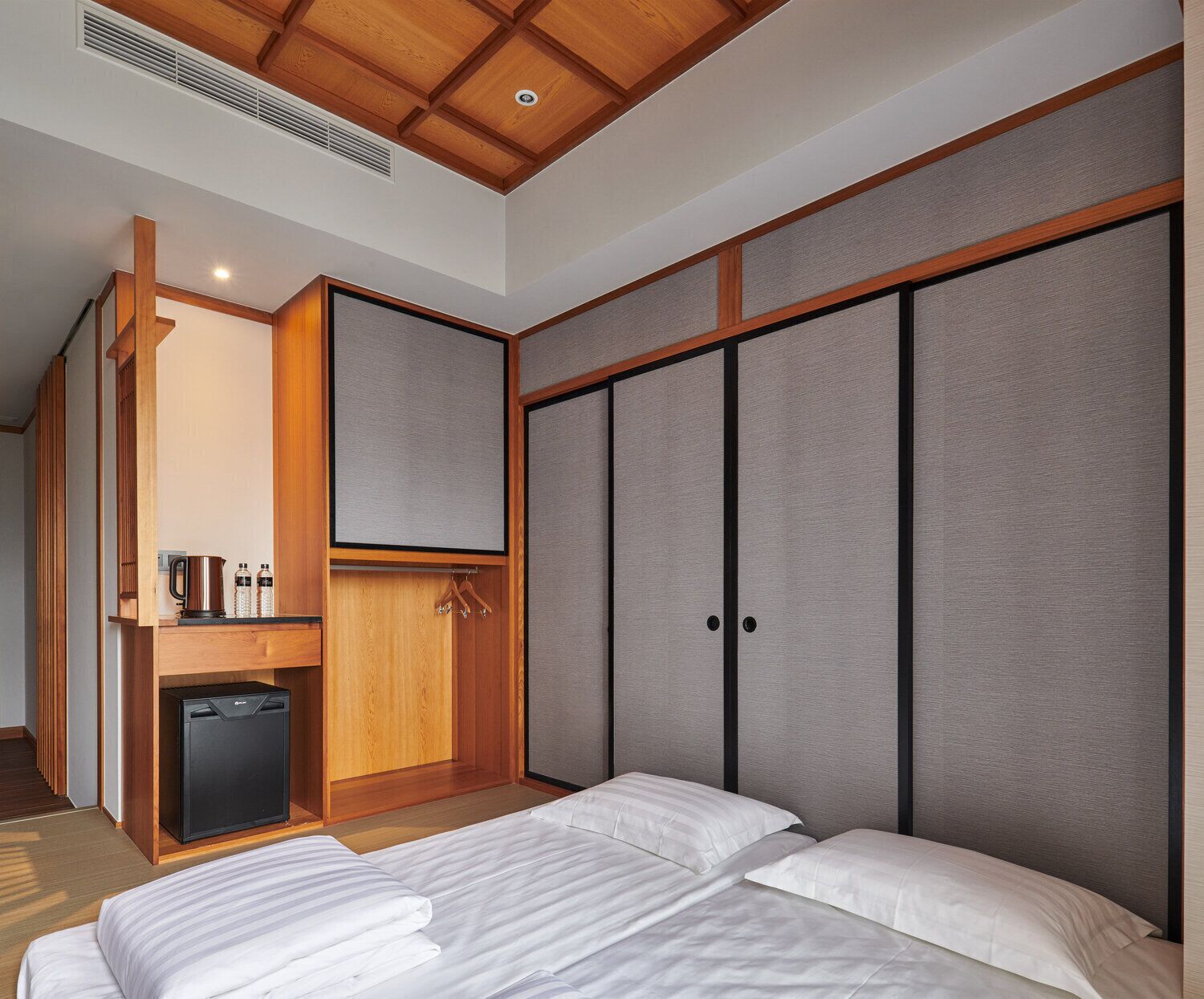 A hotel room with a bed, a small kitchenette, and a sliding wardrobe.