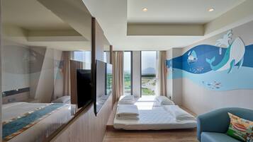 A hotel room with two beds, a TV, a large window with a view, and a mural on the wall.